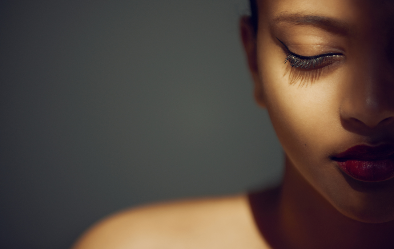 A young woman with her face partially in the shadow and partially lit with warm light