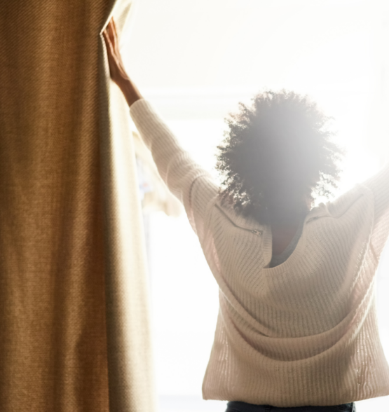 A person standing at a window with light pouring in, symbolizing new sight.